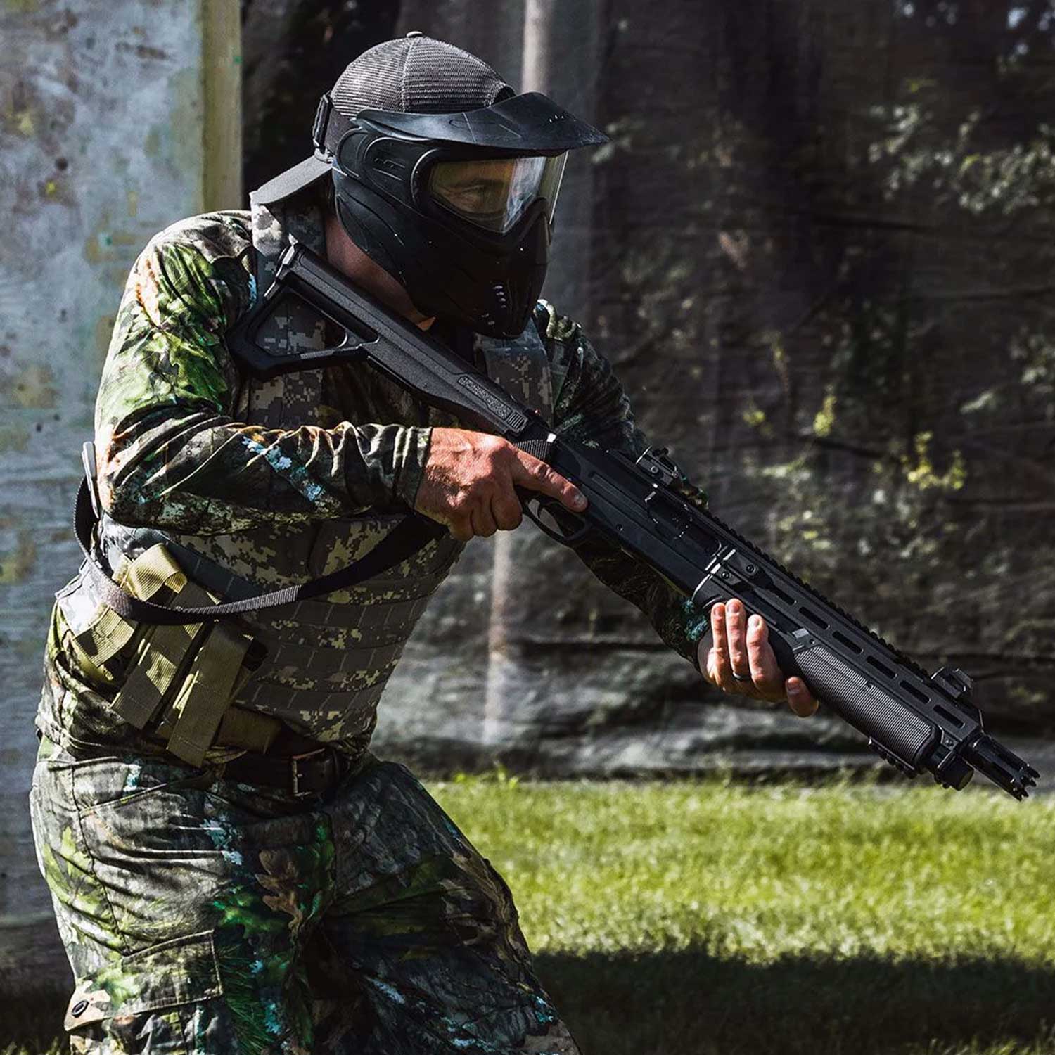 Se muestra escopeta traumática T4E TX68 en uso por persona con uniforme táctico tipo gotcha, en entorno de entrenamiento, destacando su aplicación en simulación y práctica con equipo de protección.
