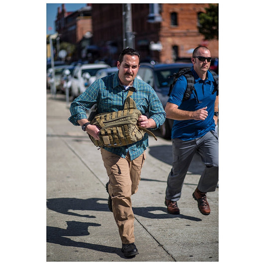 a man in a blue shirt is walking down the street